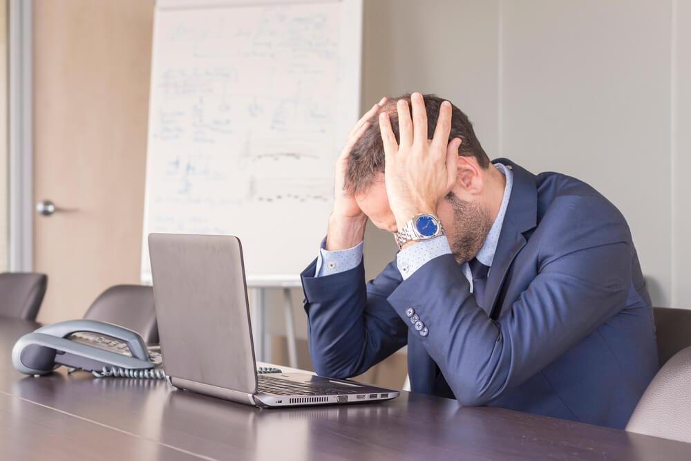 Hombre en el trabajo padeciendo de ansiedad, ya que no consigue concentrarse para terminar su trabajo