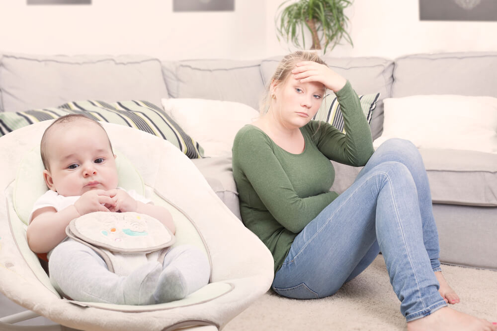 Madre sufriendo depresión post-parto al lado de se hijo